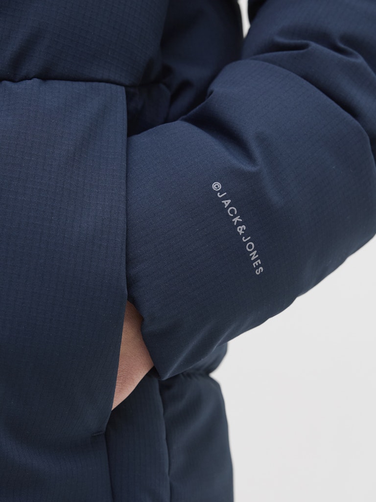 Navy blue jacket with 'Jack & Jones' branding on a light gray background