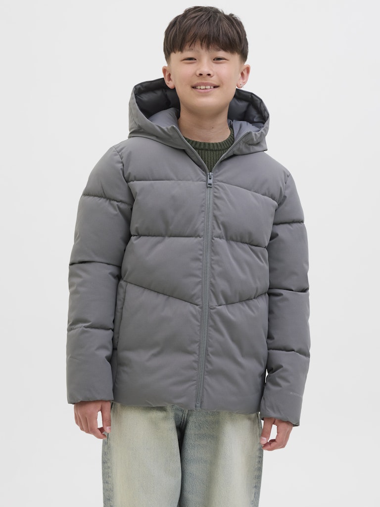 Child wearing a gray puffer jacket on a plain background