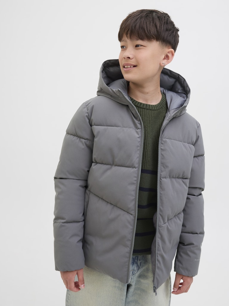 Child wearing a gray puffer jacket on a white background