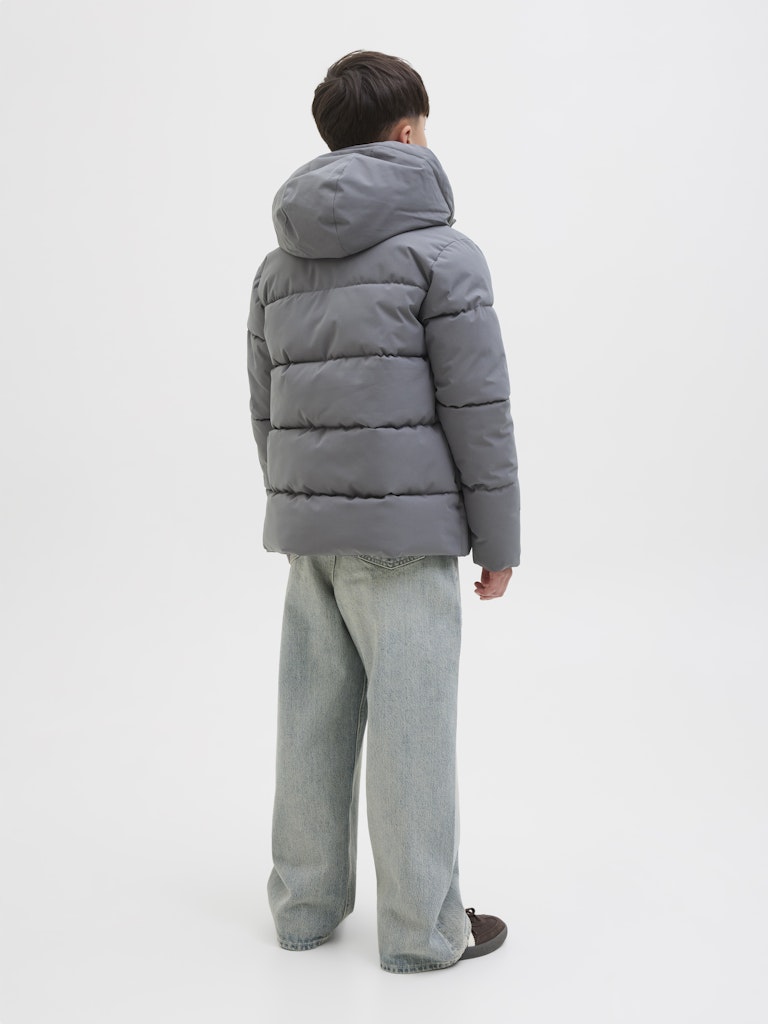 Person wearing a gray puffer jacket and pants on a white background