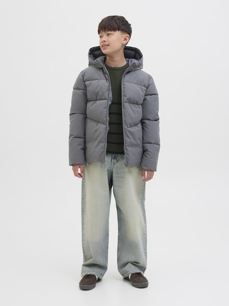 Child wearing a gray puffer jacket and jeans on a white background