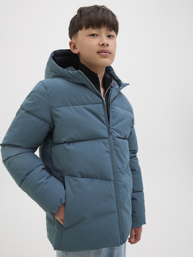 Child wearing a blue puffer jacket on a white background