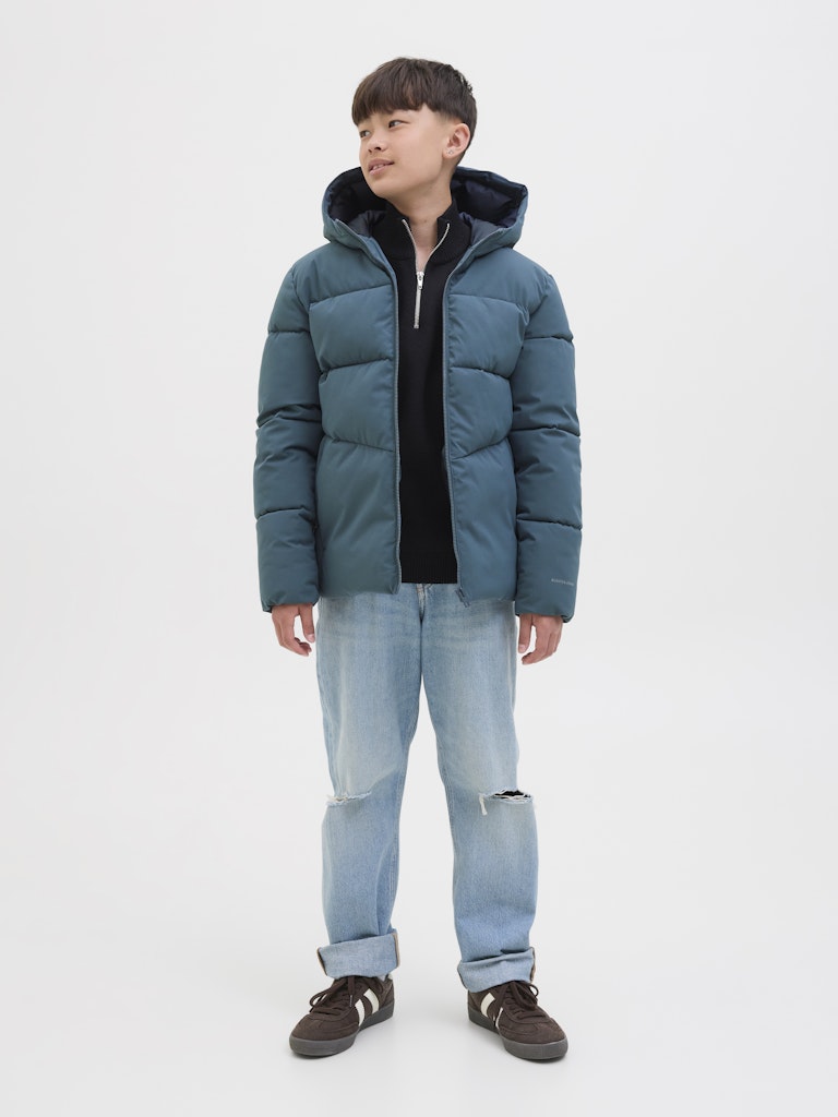 Person wearing a blue puffer jacket and light blue jeans on a white background
