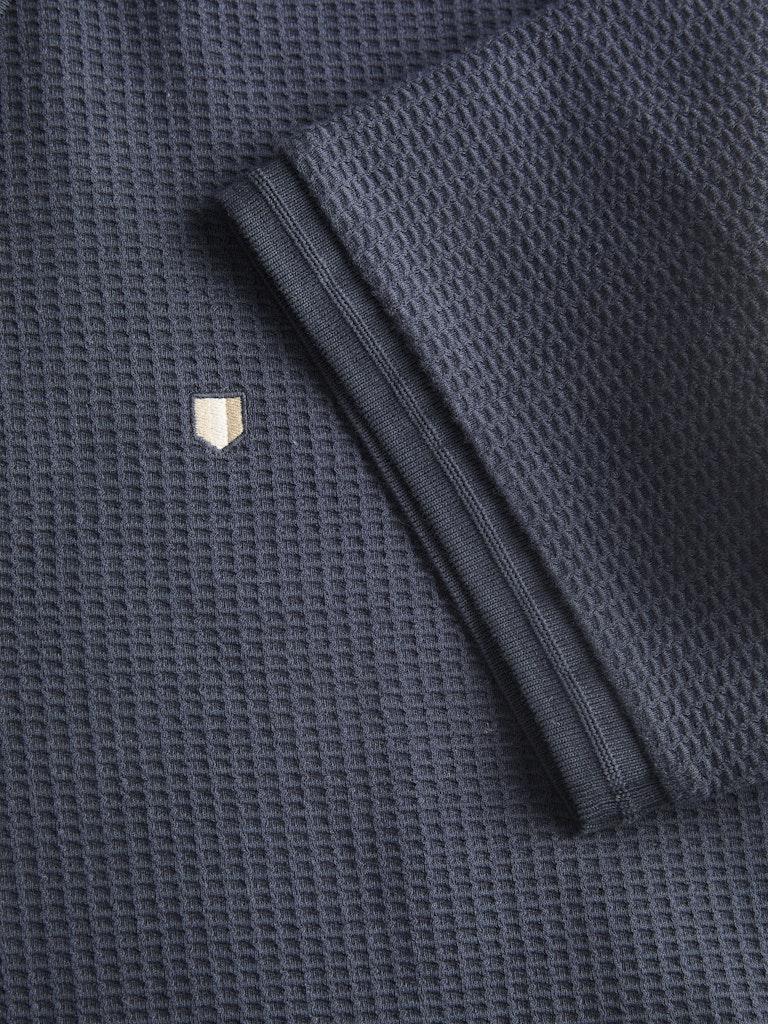 Dark blue textured fabric with a folded sleeve on a matching background