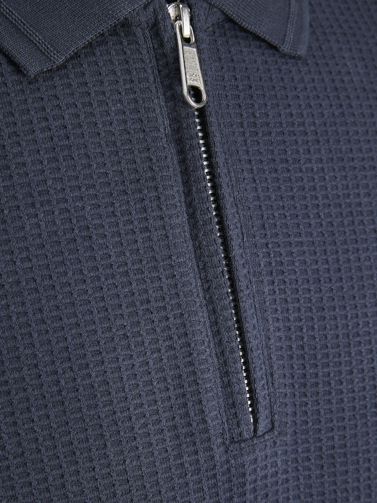 Close-up of a textured navy blue zip-up polo shirt with a zipper detail.