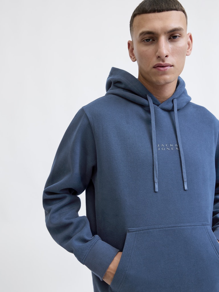 Man wearing a blue hoodie with a brand logo on a white background