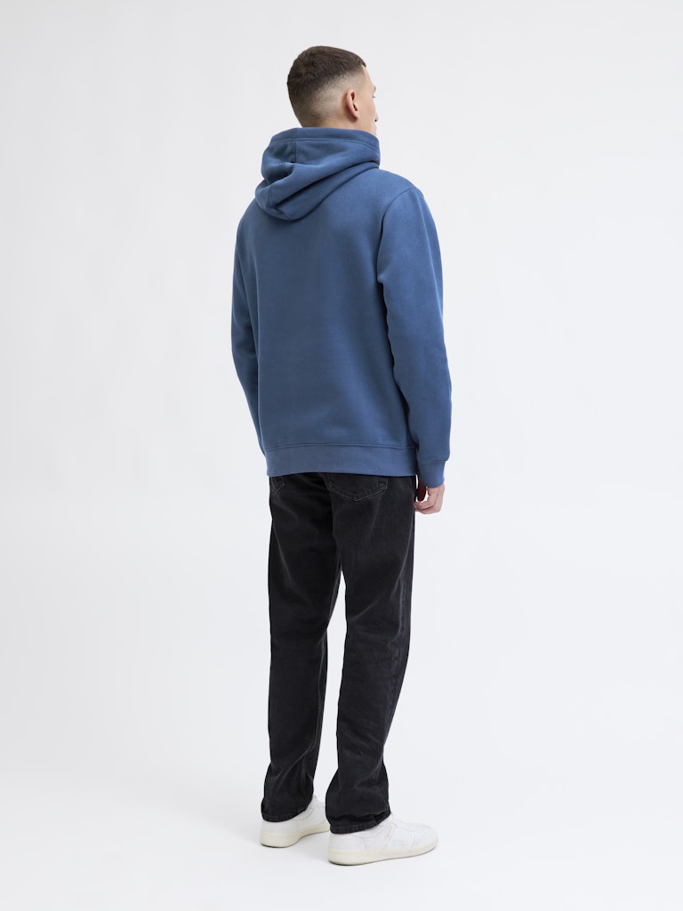 Person wearing a blue hoodie and black pants on a white background