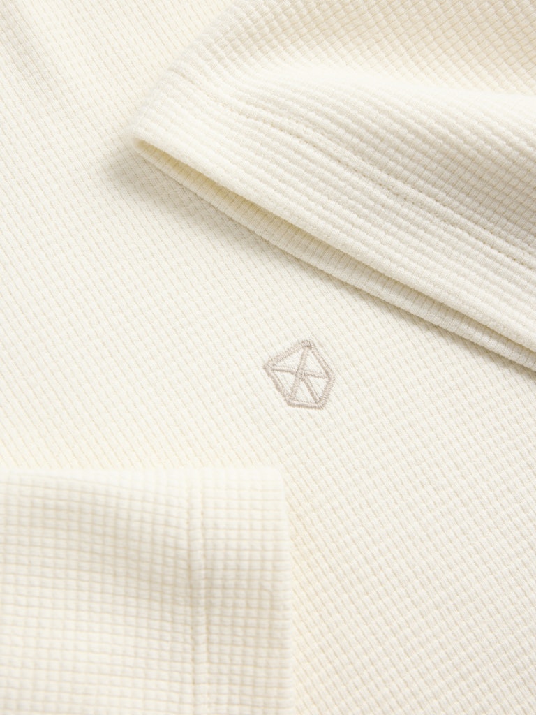 Close-up of a textured white fabric with a subtle logo.