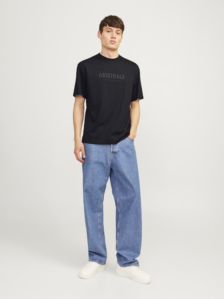 Person wearing a black t-shirt with 'ORIGINALS' text and blue jeans on a white background