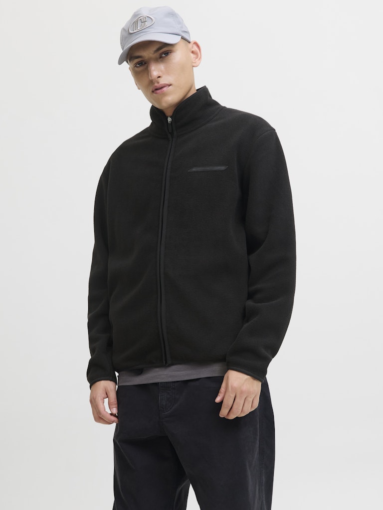 Man wearing a black jacket and cap on a white background