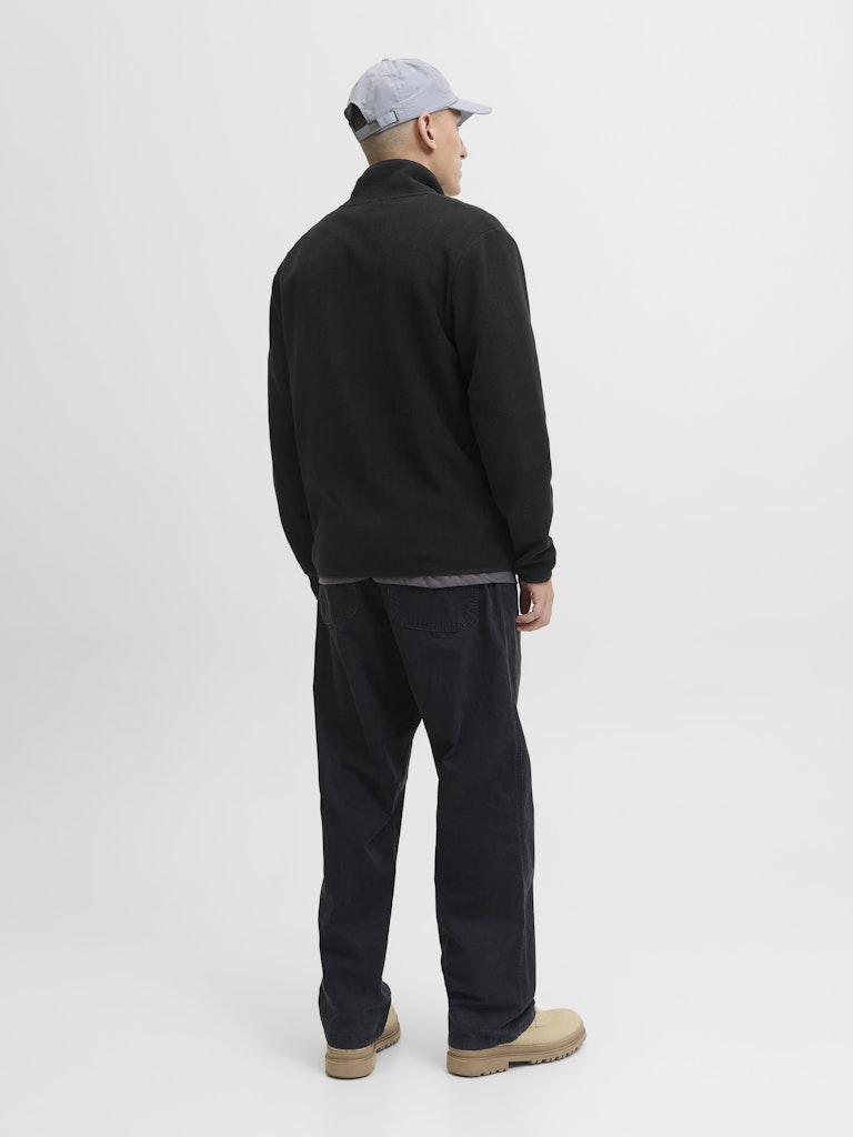 Person wearing a black jacket and pants with a gray cap on a white background