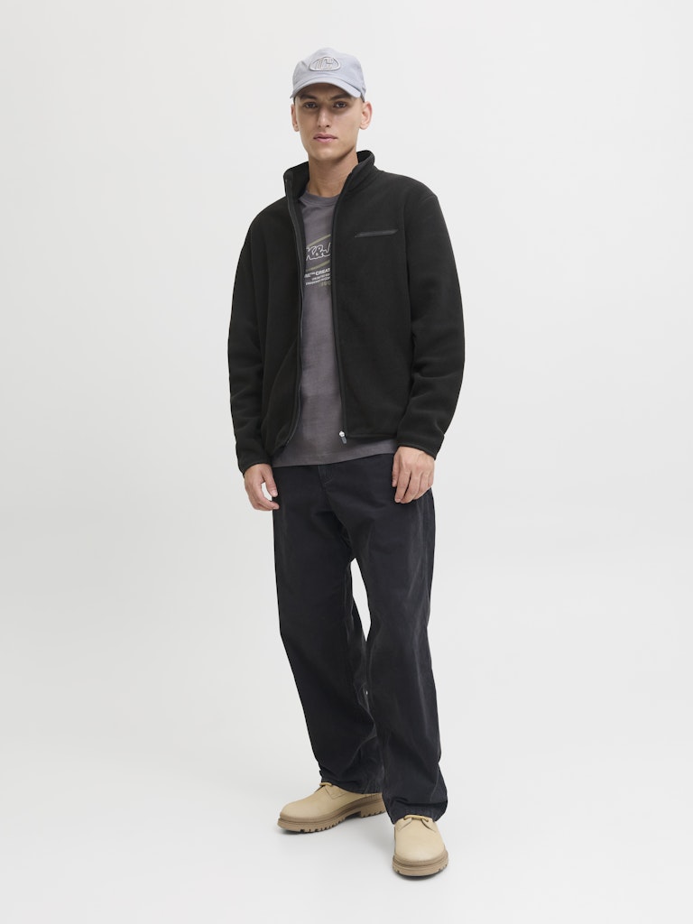 Man wearing a black jacket, gray cap, gray shirt, black pants, and beige shoes on a white background