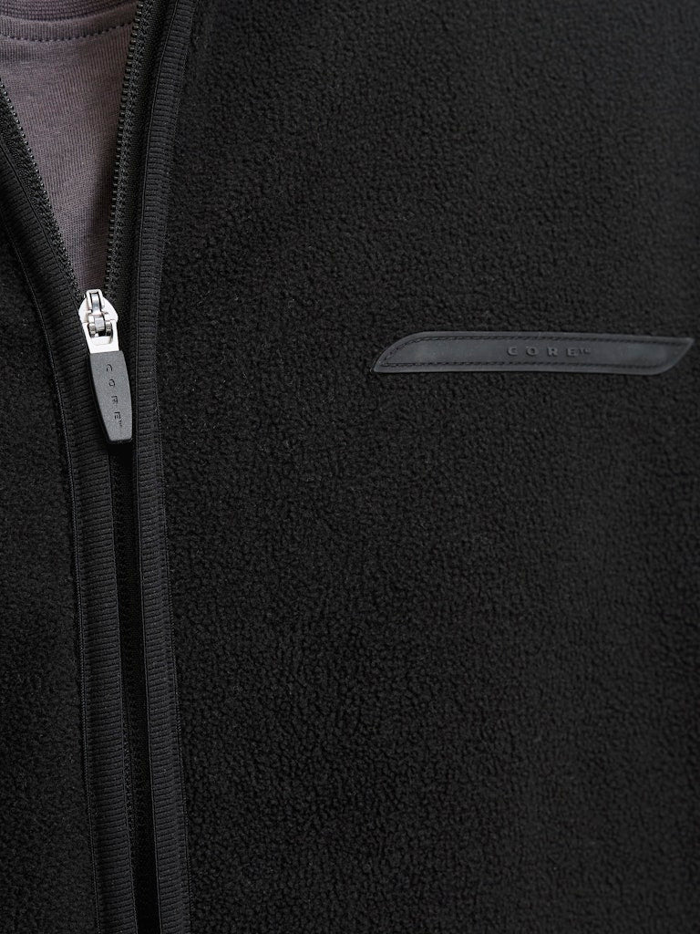 Close-up of a black fleece jacket with a zipper and brand logo.