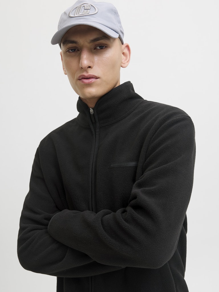 Person wearing a black jacket and gray cap on a white background