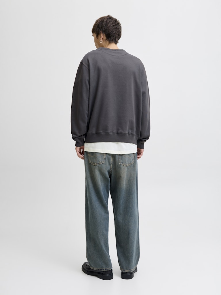 Man wearing a grey sweatshirt and blue jeans