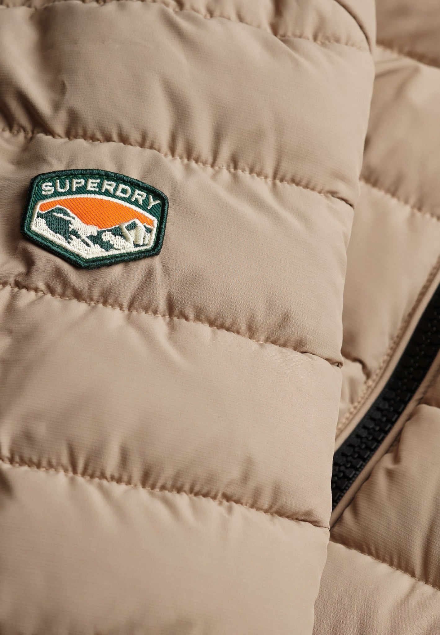 Superdry Fuji Midweight Padded Jacket in Buckwheat Beige logo patch detail