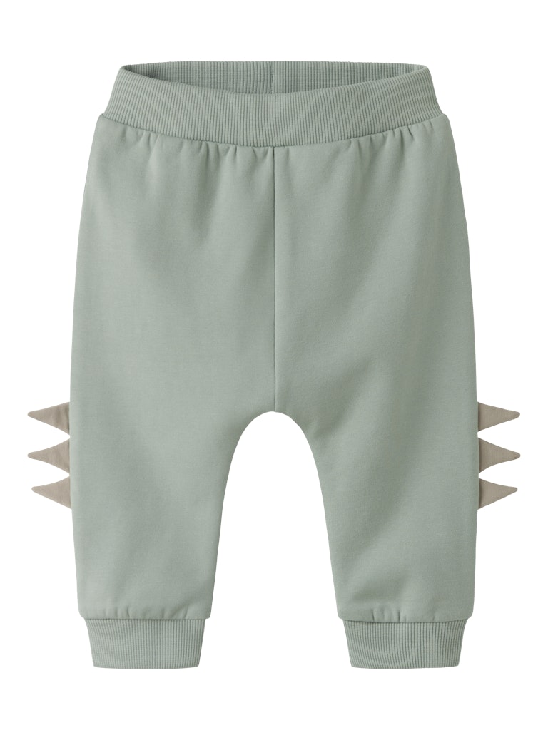 Light green children's pants with dinosaur spikes on a white background