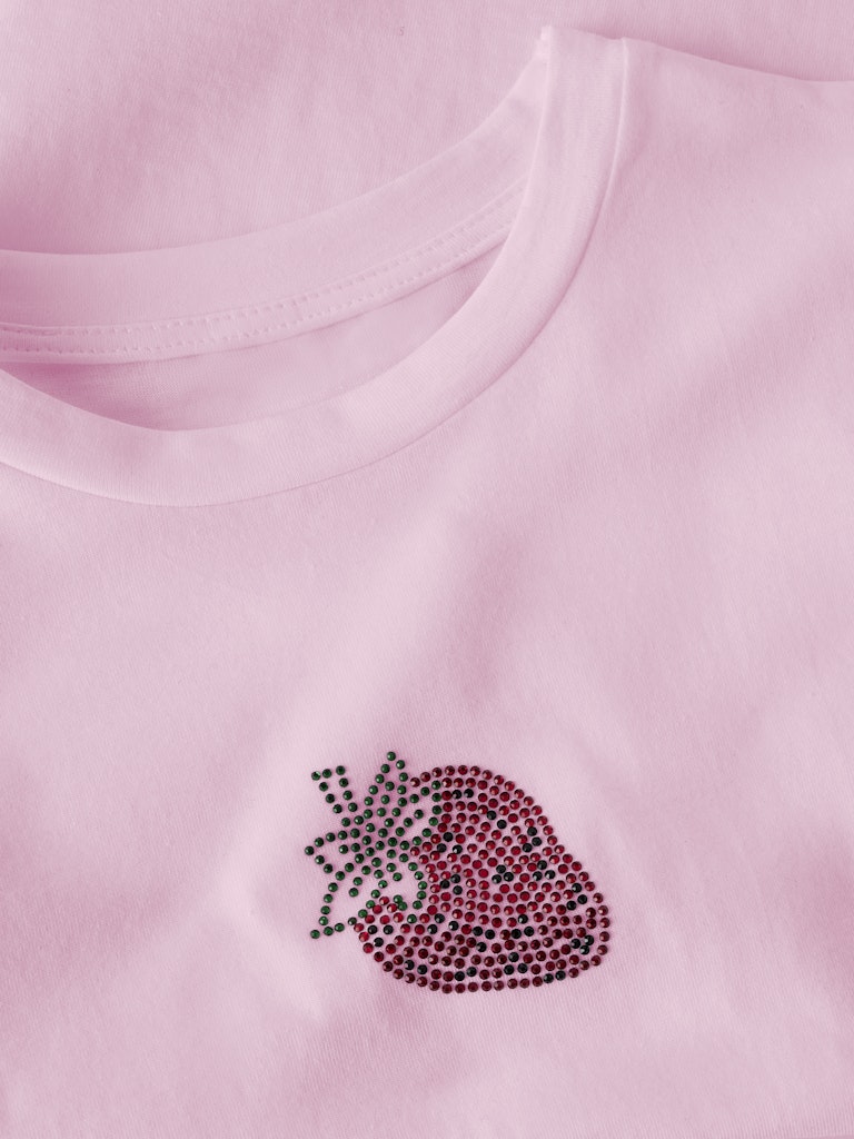 Pink fabric with a decorative heart design made of small stones or beads.