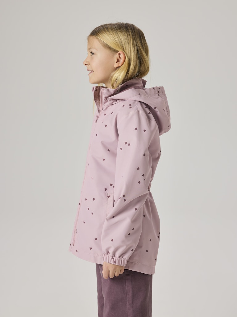 Child wearing a pink raincoat with heart patterns on a light gray background