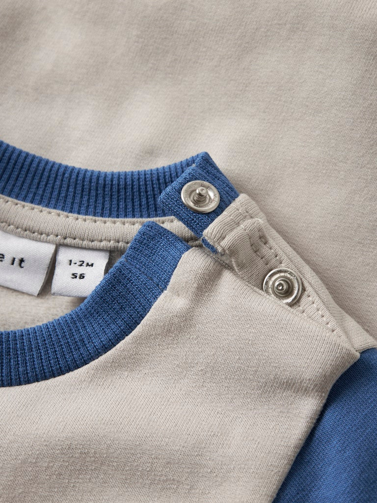 Close-up of a baby outfit with blue and gray colors and a label.