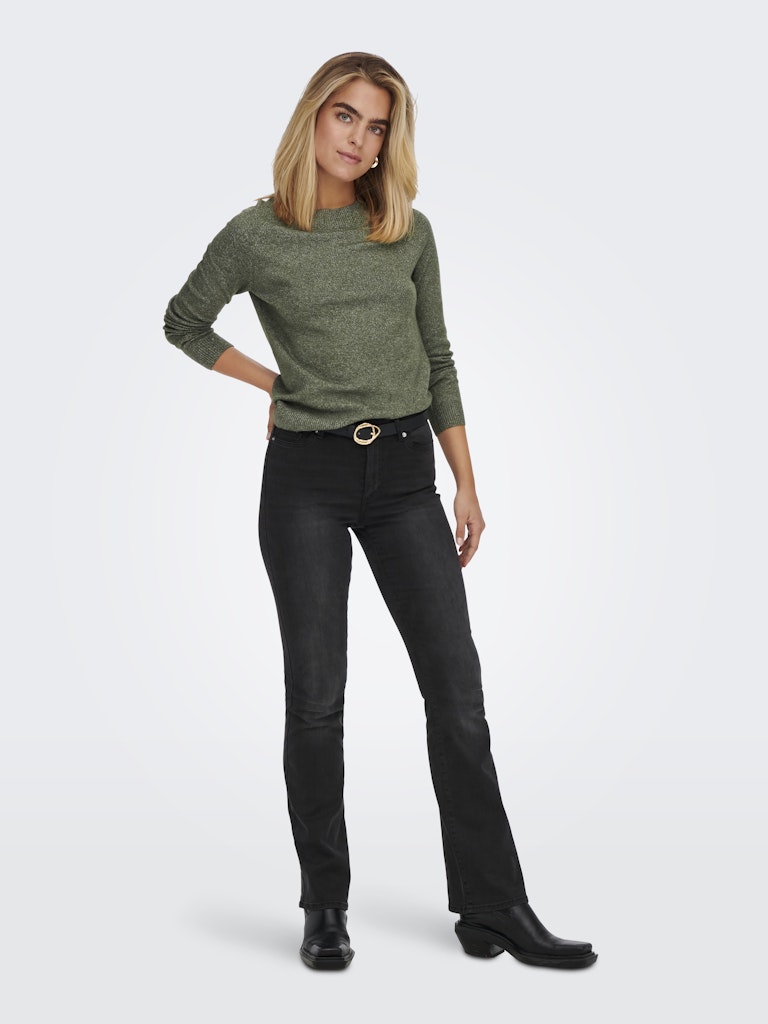 Woman wearing a green sweater and black jeans on a white background
