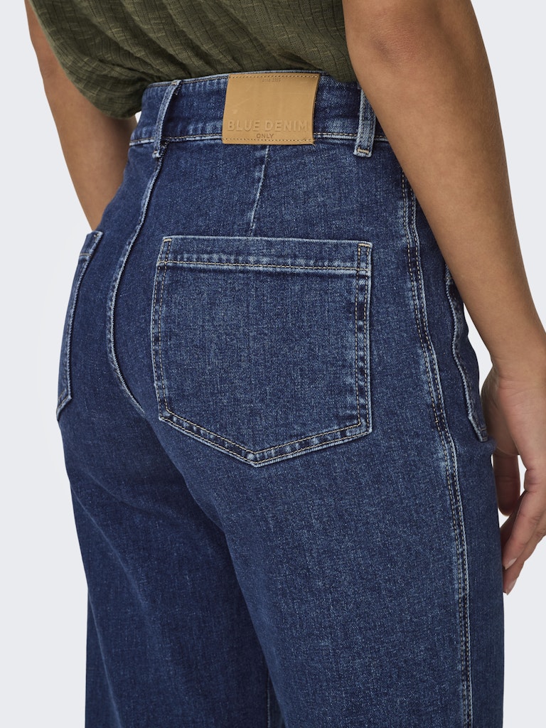 Blue jeans with a brown patch on a white background
