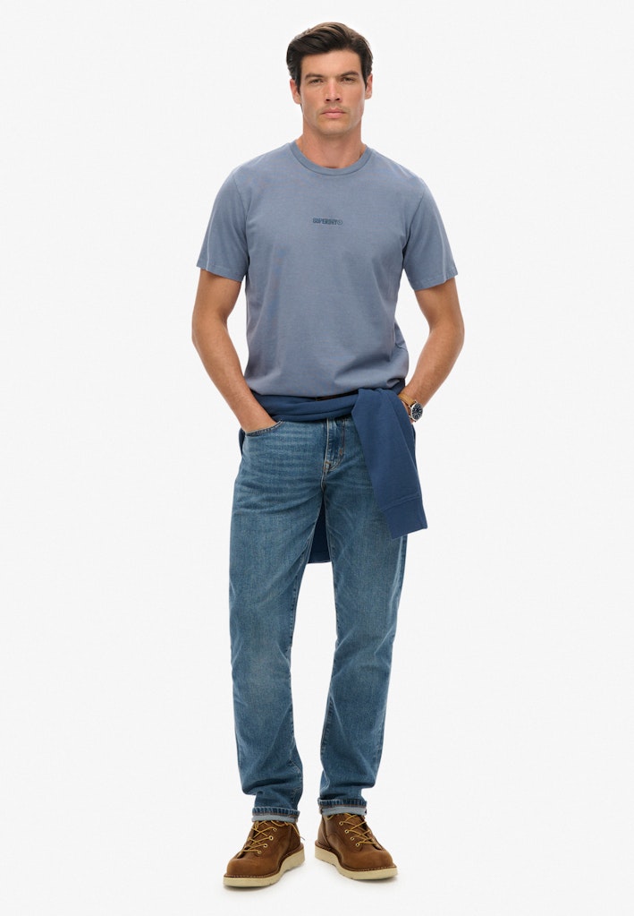 Man wearing a blue t-shirt and jeans on a white background