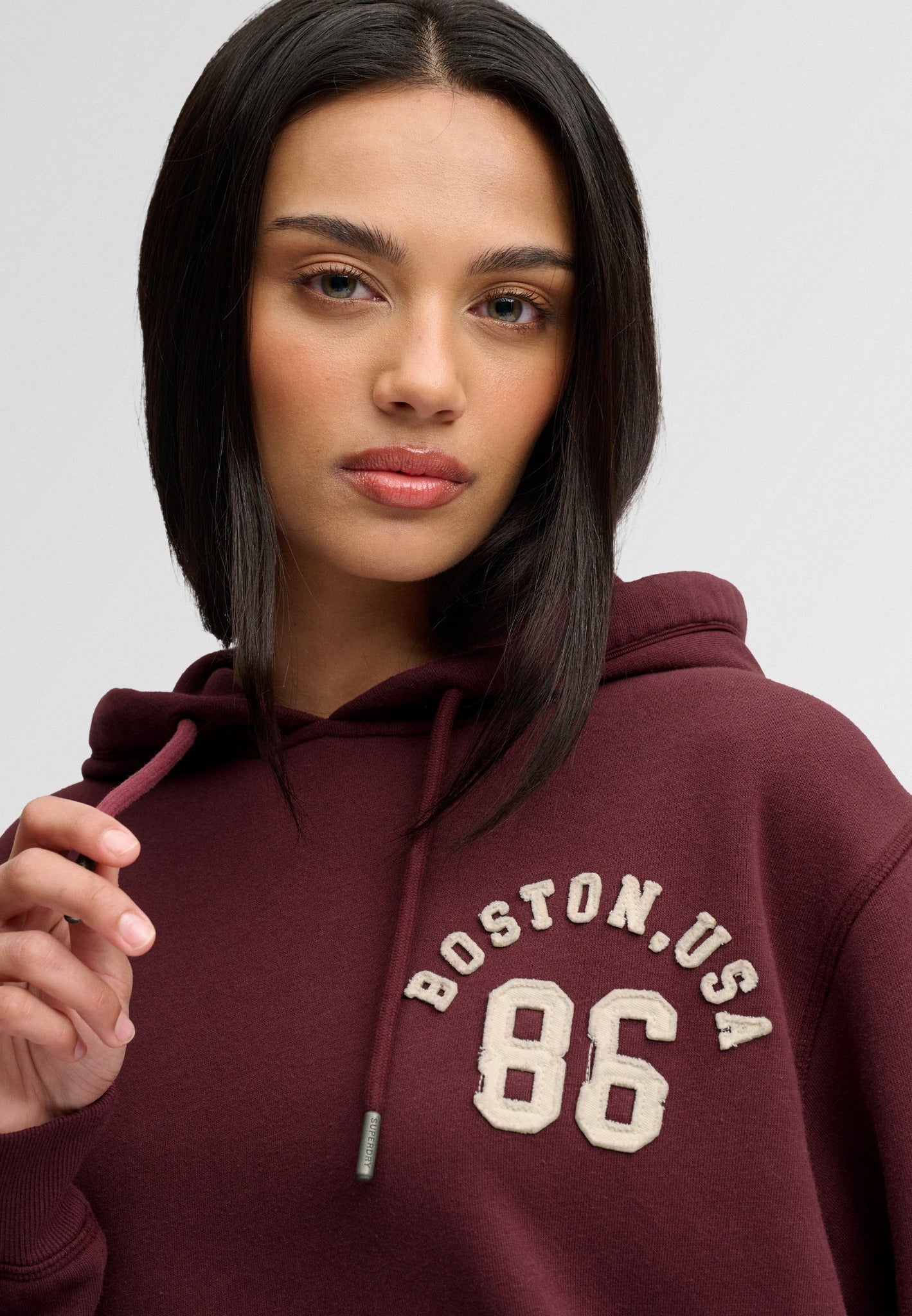 Superdry Ath Essential Applique Crop Hood in Port Red applique angled view