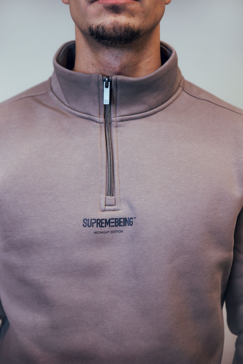 Close-up of the Titan Taupe stand collar, metal zip and Midnight Edition chest logo