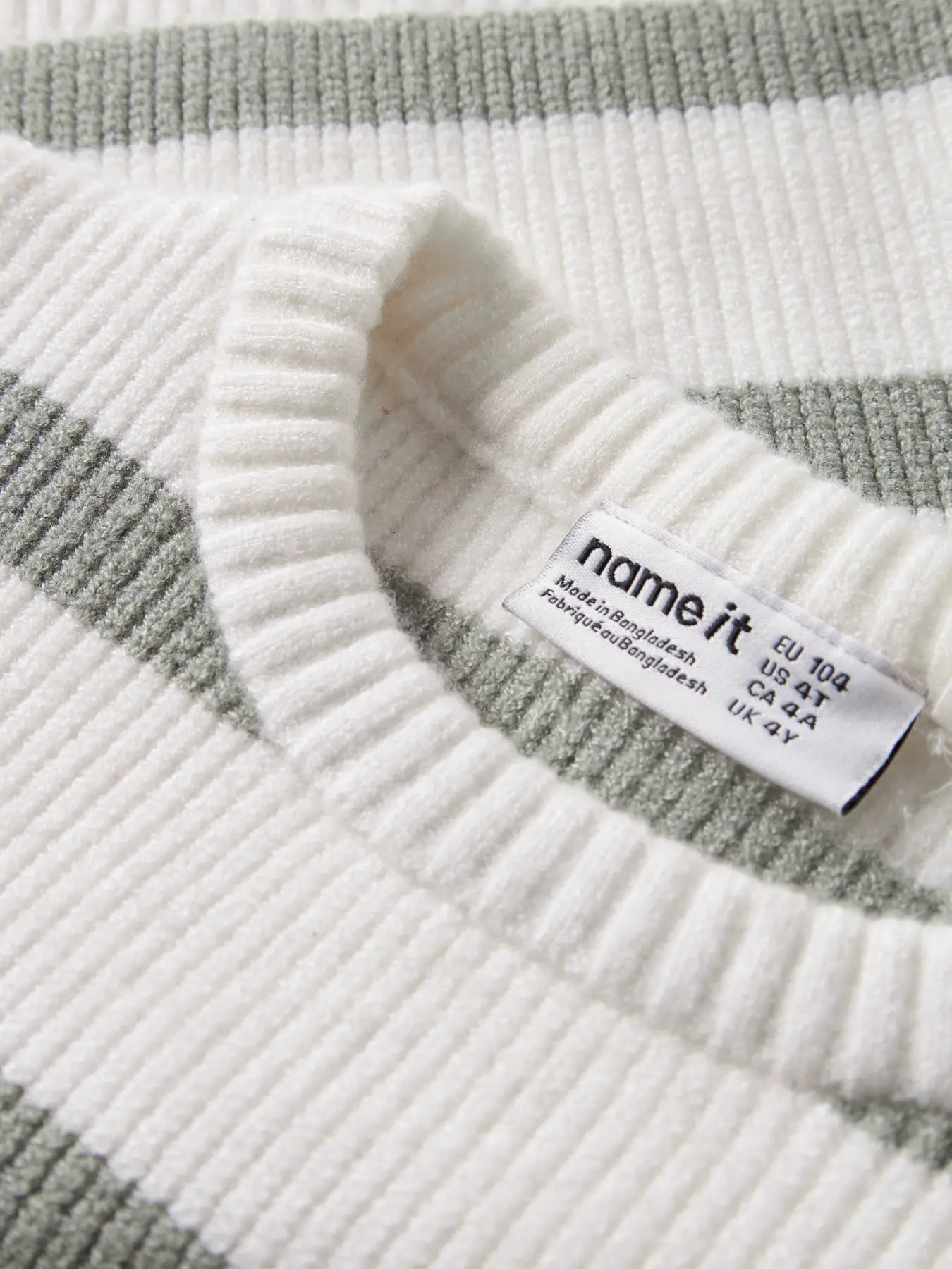 Close-up of a striped sweater with a brand label on a white background