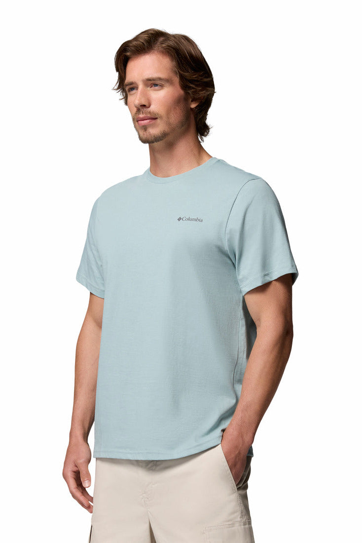 Man wearing a light blue t-shirt with a brand logo on a white background