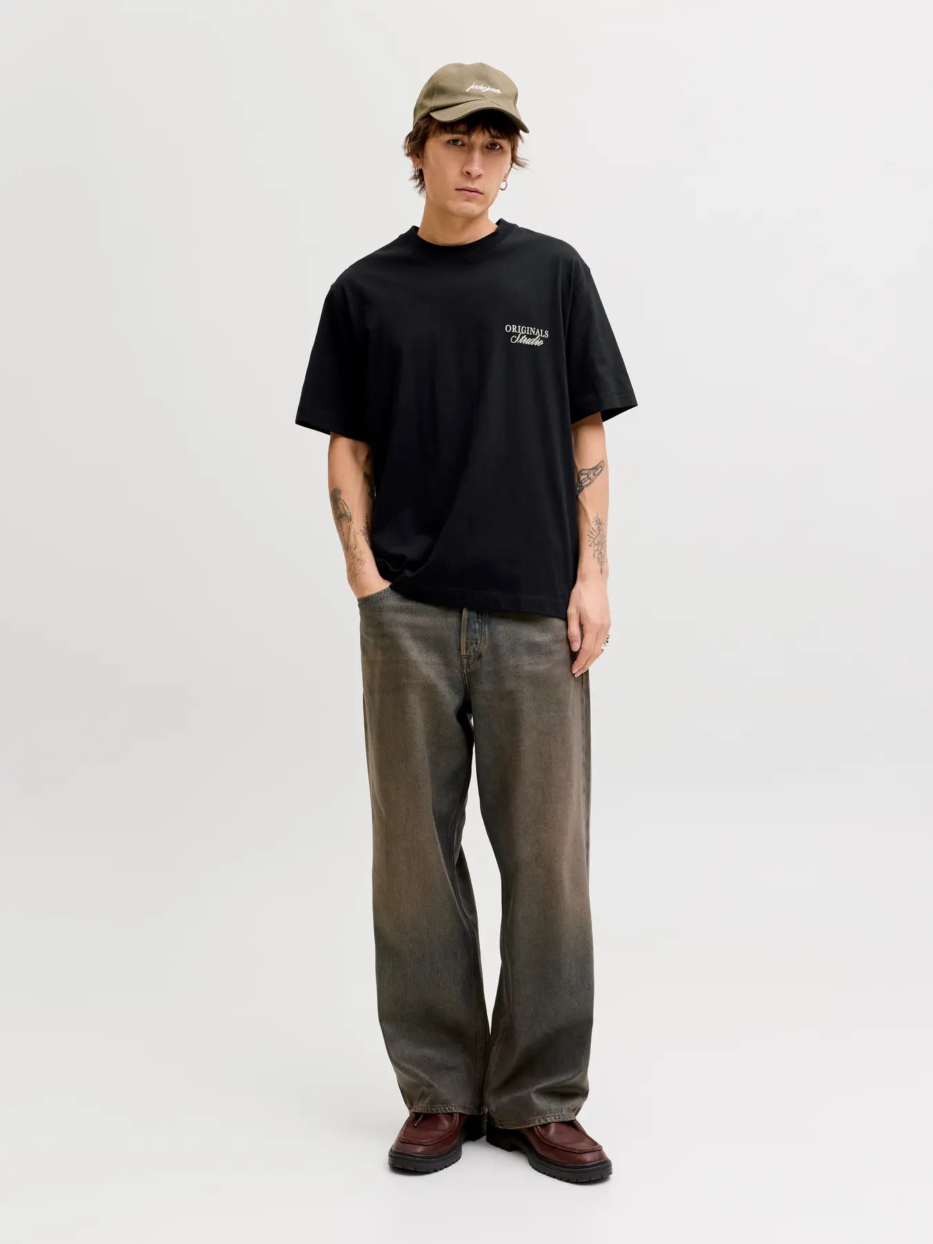 Person wearing a black t-shirt, green cap, and brown pants on a white background