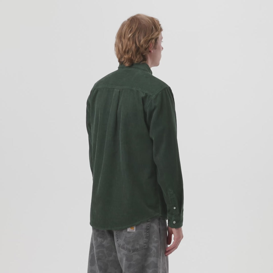 Video of a man wearing a green corduroy shirt on a light gray background