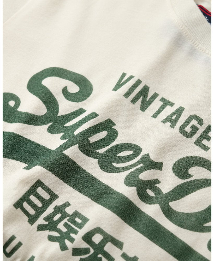 Close-up of a white tee with green text and logos, including 'Superdry' and 'Vintage'.