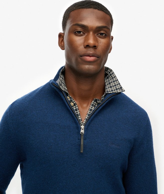 Man wearing a blue sweater with plaid collar against a white background