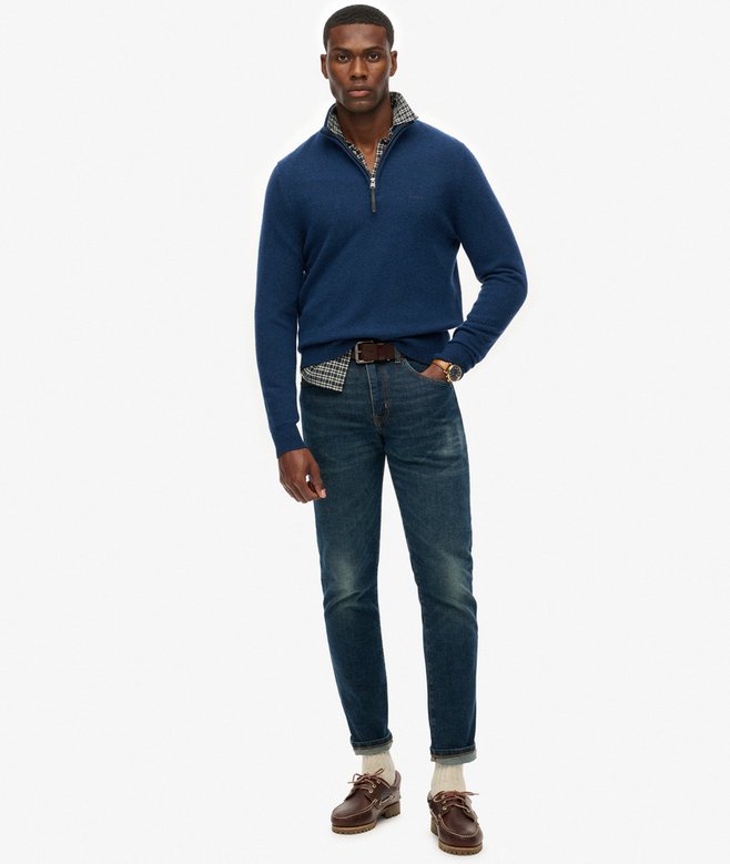 Man wearing a blue sweater and jeans on a white background