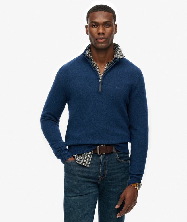 Man wearing a blue sweater with plaid collar and jeans on a white background