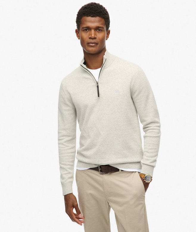 Man wearing a light gray half-zip sweater and beige pants on a white background