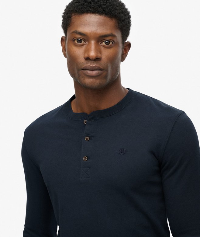 Man wearing a navy long-sleeve henley shirt against a white background