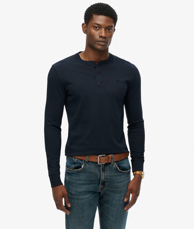 Man wearing a dark blue long-sleeve shirt and jeans on a white background