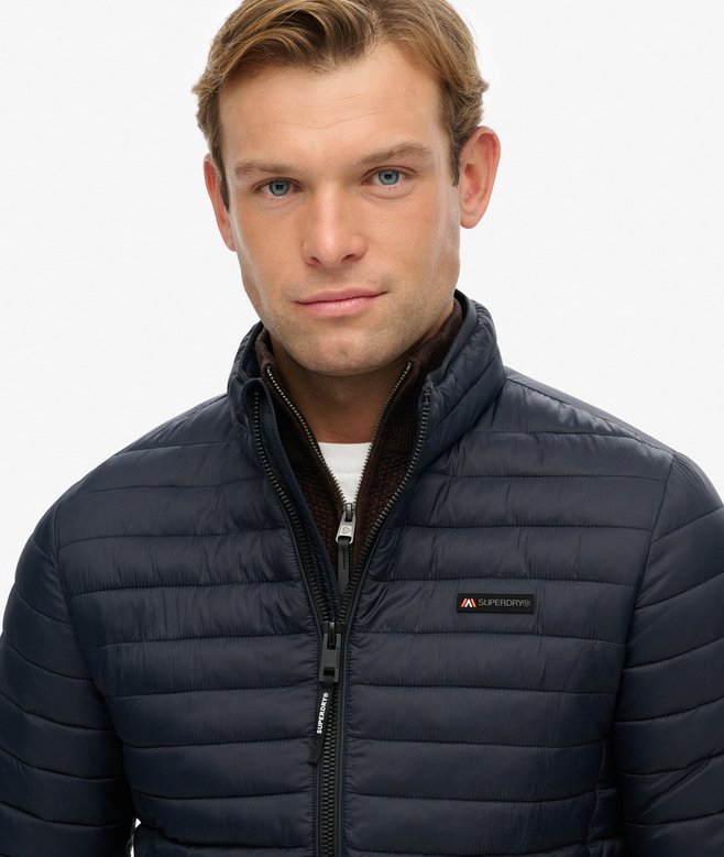 Man wearing a navy blue puffer jacket with a brand logo on a white background