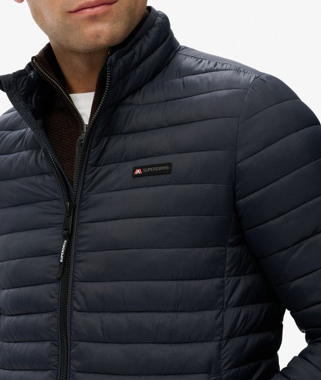 Close-up of a person wearing a navy blue puffer jacket with a brand logo on a white background