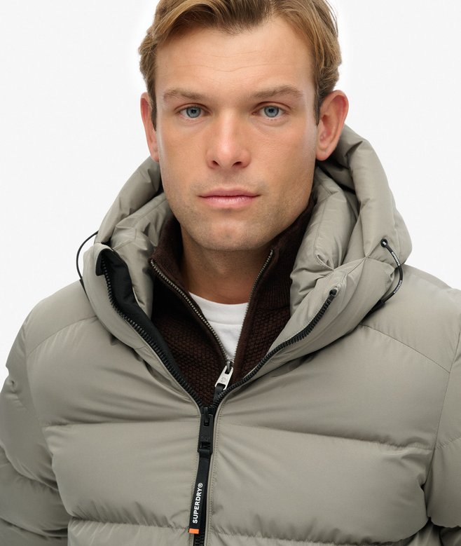 Man wearing a light green puffer jacket on a white background