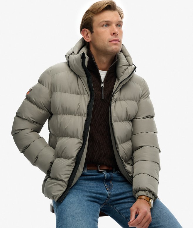 Man wearing a light green puffer jacket on a white background