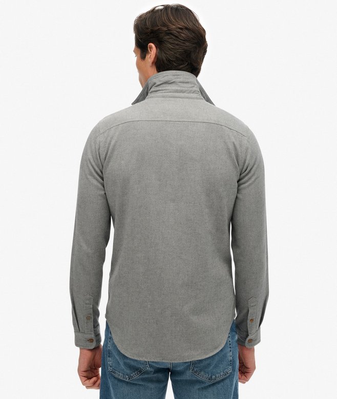 Man wearing a blue-gray long-sleeve shirt and blue jeans on a white background