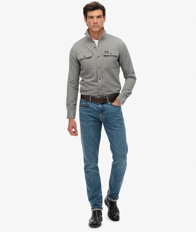 Man wearing a blue-gray shirt and blue jeans on a white background