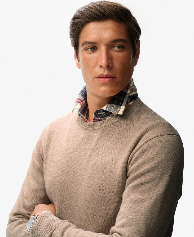 Man wearing a beige sweater with a plaid collar on a white background
