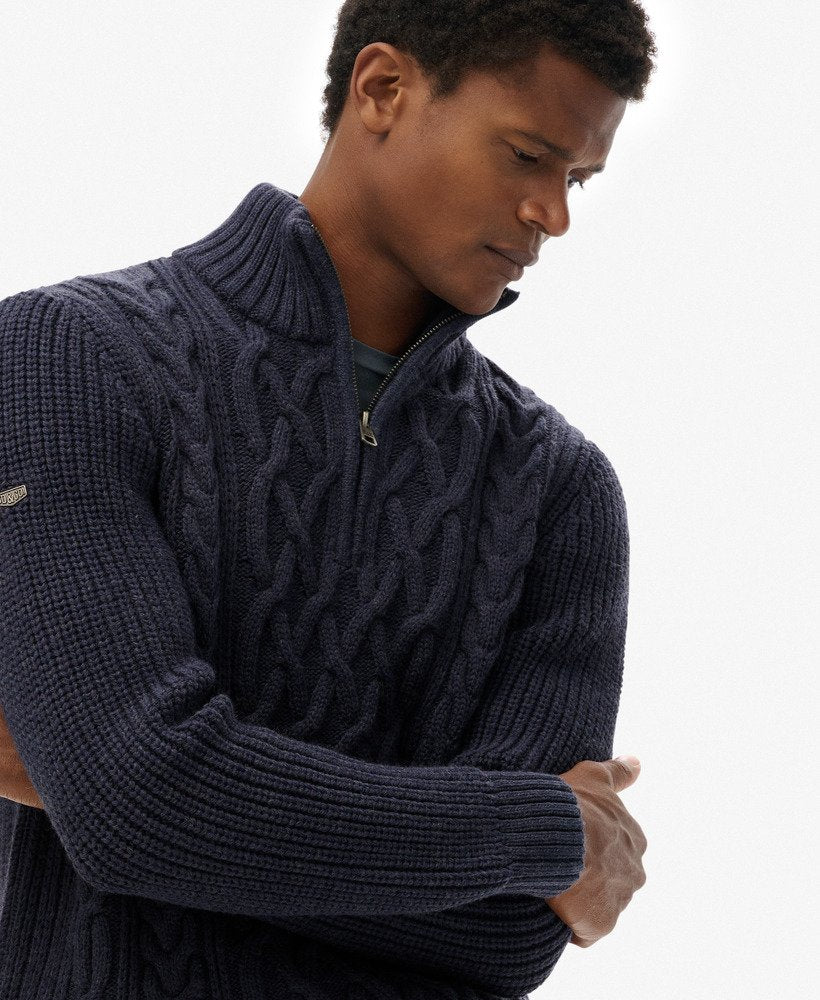 Man wearing a dark blue cable knit sweater on a white background
