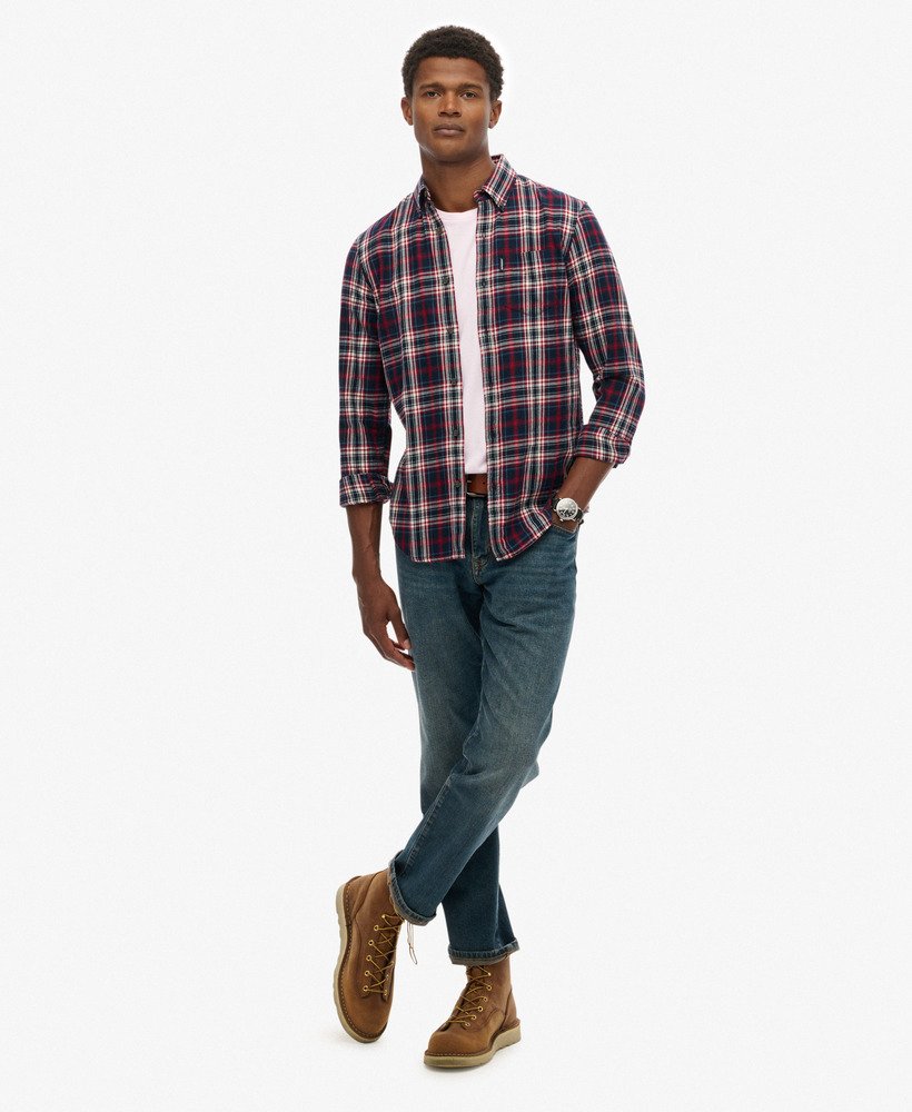 Man wearing a plaid shirt, jeans, and brown boots on a white background