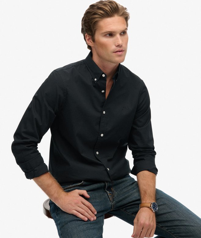 Man wearing a black button-up shirt and jeans on a white background